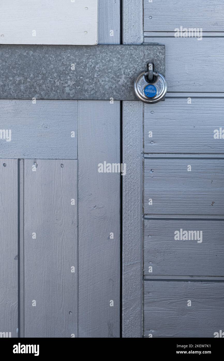 Tür einer Strandhütte mit Vorhängeschloss in Grau- und Blautönen Stockfoto