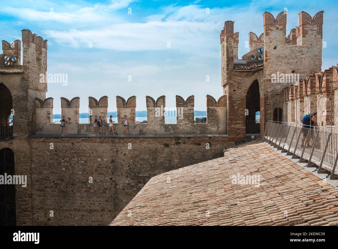 Scaligero Castle Sirmione, Blick im Sommer von weiblichen Touristen erkunden die Zinnen der Westwand der mittelalterlichen Burg Scaligero, Gardasee Stockfoto