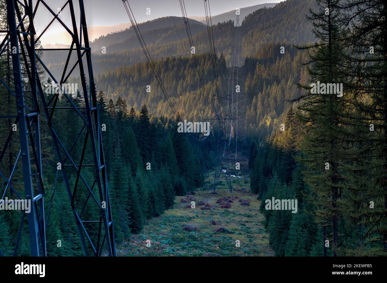 Hochspannungsleitungen überqueren eine Bergspitze und ein Tal. Stockfoto