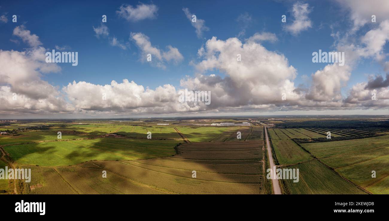 Grünes landwirtschaftliches Feld mit Wolken Schatten und Lichtflecken unter bewölktem Himmel Luftpanorama. Horizont über landschaftlich reizvoller Landschaft Stockfoto