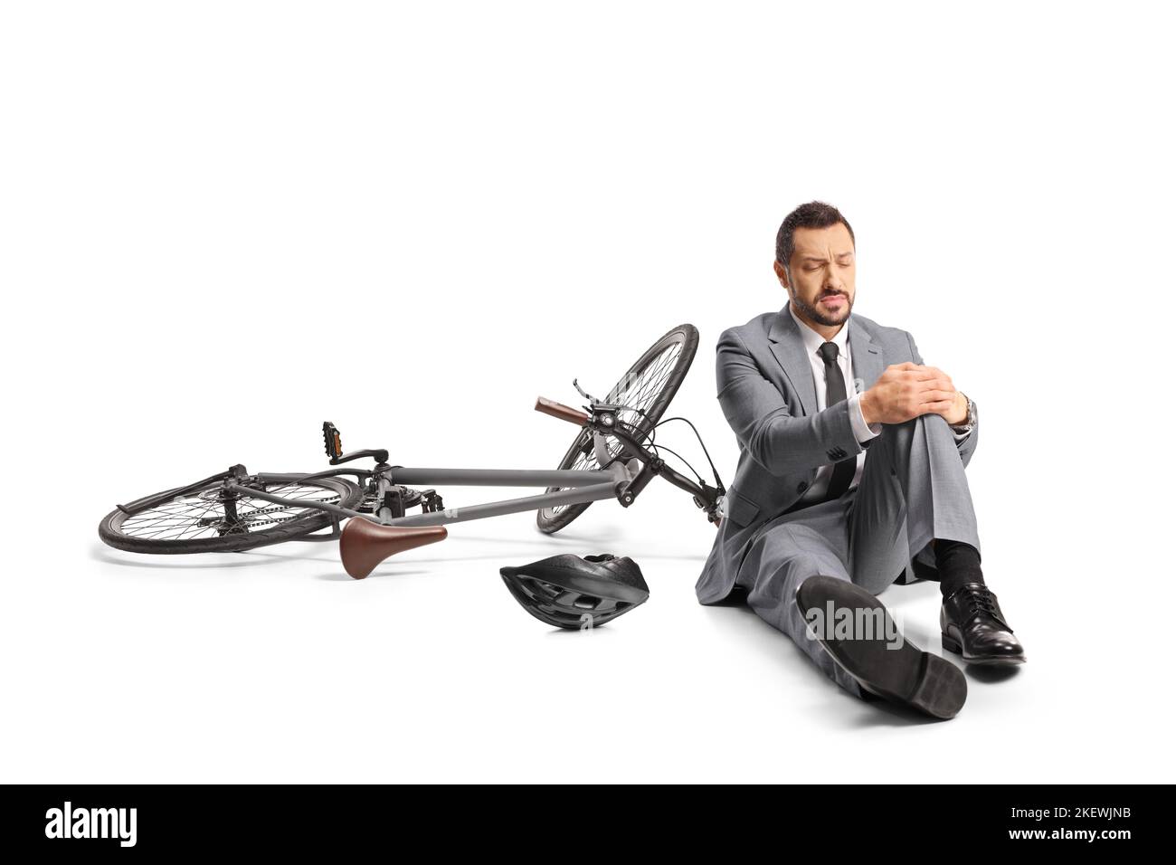 Geschäftsmann fällt von einem Fahrrad und hält sein Knie isoliert auf weißem Hintergrund Stockfoto