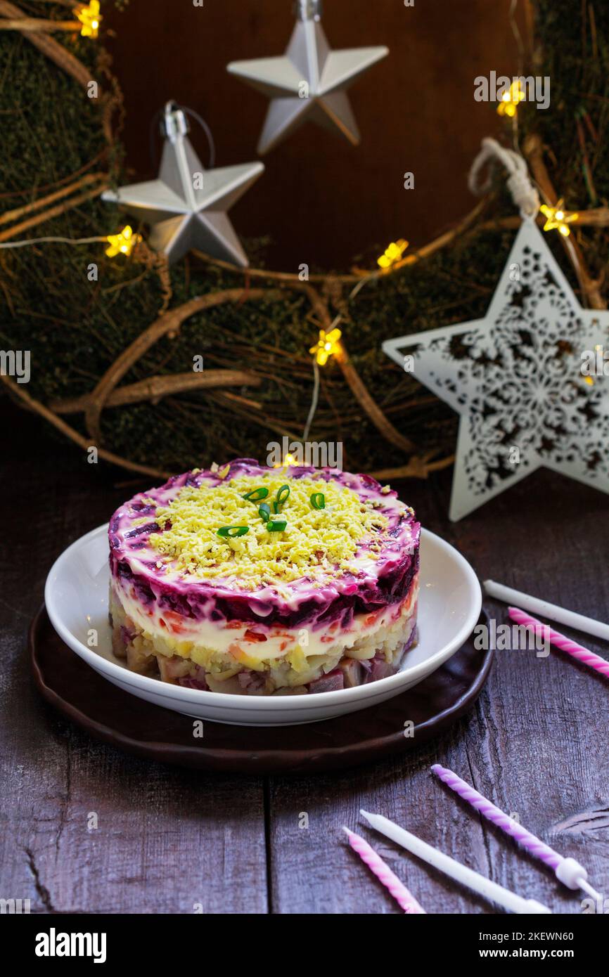 Gekleideter Hering, weihnachtliche sowjetische Salate aus Hering und Gemüse in einer Neujahrsdekoration. Stockfoto