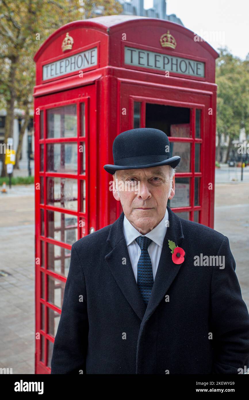 englischer Gentleman in Melone Hut vor der traditionellen britischen roten Telefonbox Stockfoto