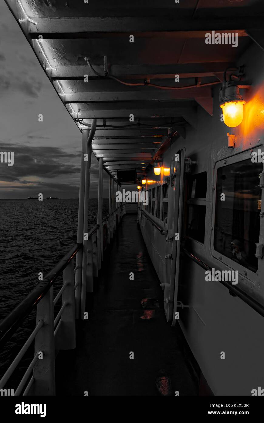 Bunte Lichter bei der abendlichen Bootstour auf dem Meer. Schwarz-weiße Postkarte von einem Kreuzfahrtschiff. Bunte Lichter in einem Schwarzweißfoto. Stockfoto