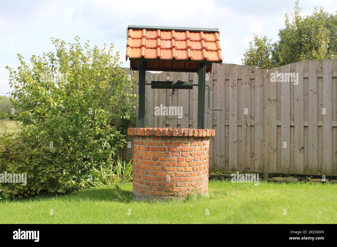 Ein historischer Wasserbrunnen auf grünem Gras in einem Garten zum Bewässern von Blumen und Gemüse Stockfoto