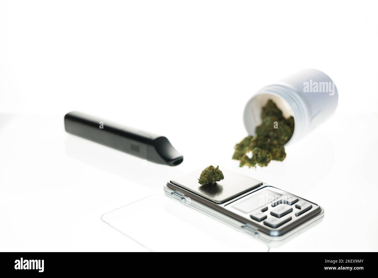 Cannabis flos, medizinisches Marihuana in weißem Behälter neben Präzisionswaage und Verdampfer, sichere Weise, Medizin zu nehmen Stockfoto