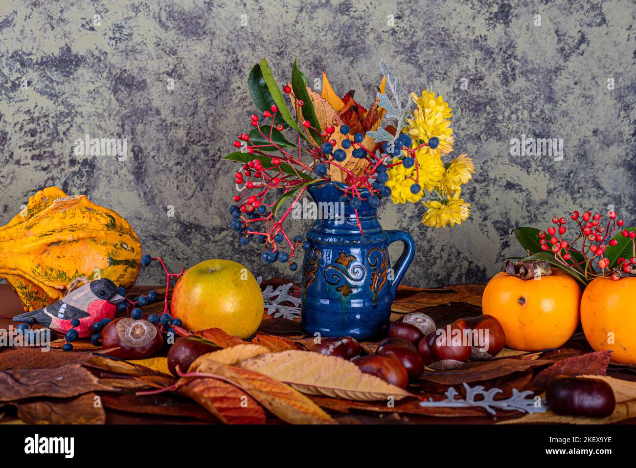 Herbstkomposition. Herbstkomposition bestehend aus Chrysanthemen, Kürbissen, Herbstblättern und Kastanien, Kaki. Stockfoto