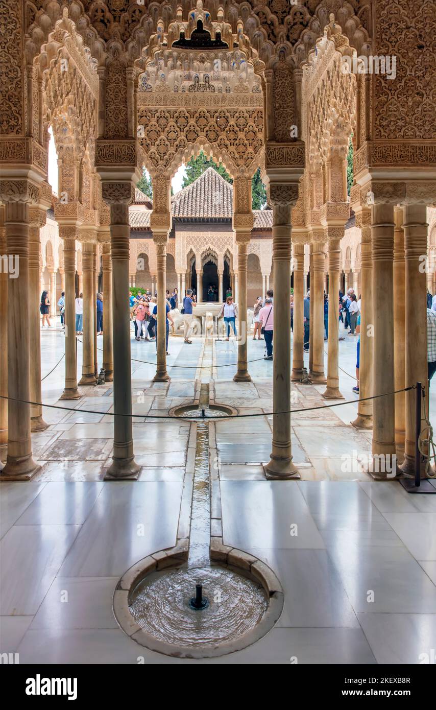 Menschen, die durch Säulen betrachtet werden, versammeln sich um den Löwenbrunnen in der Alhambra, Granada, Andalusien, Spanien Stockfoto