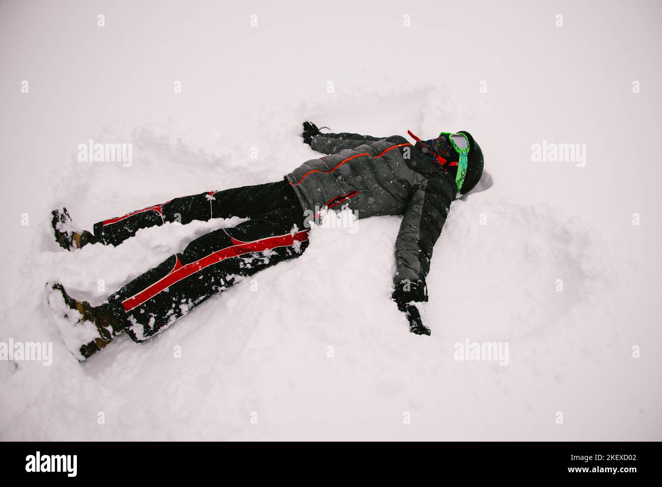 Pre teen Kind macht Schnee Winkel in Winterkleidung und weißen Boden Stockfoto