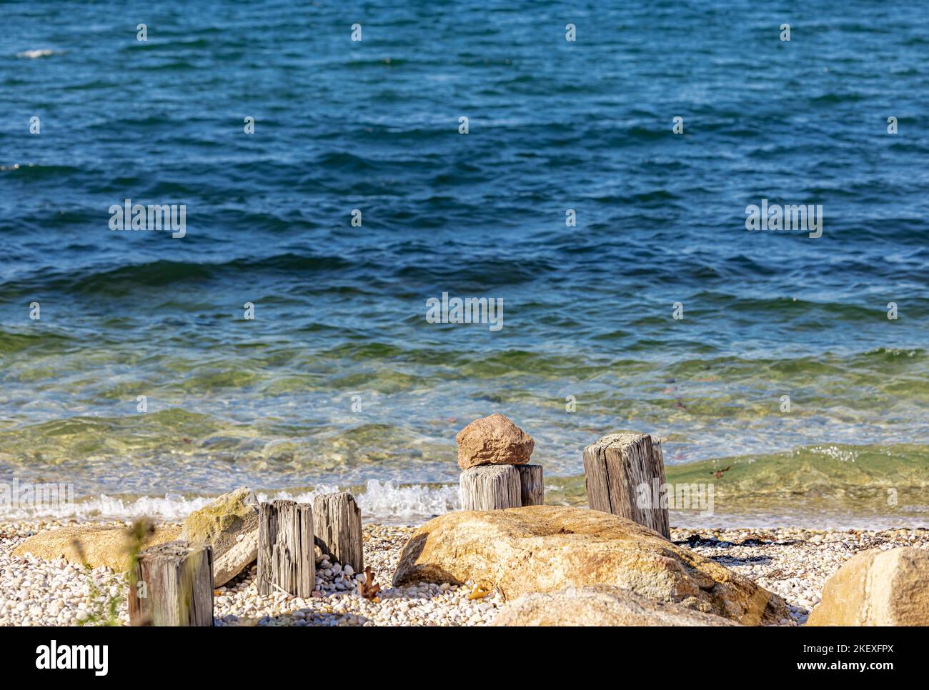 Das Stillleben am Strand besteht aus einem Felsen, der auf einem alten Peiling liegt Stockfoto