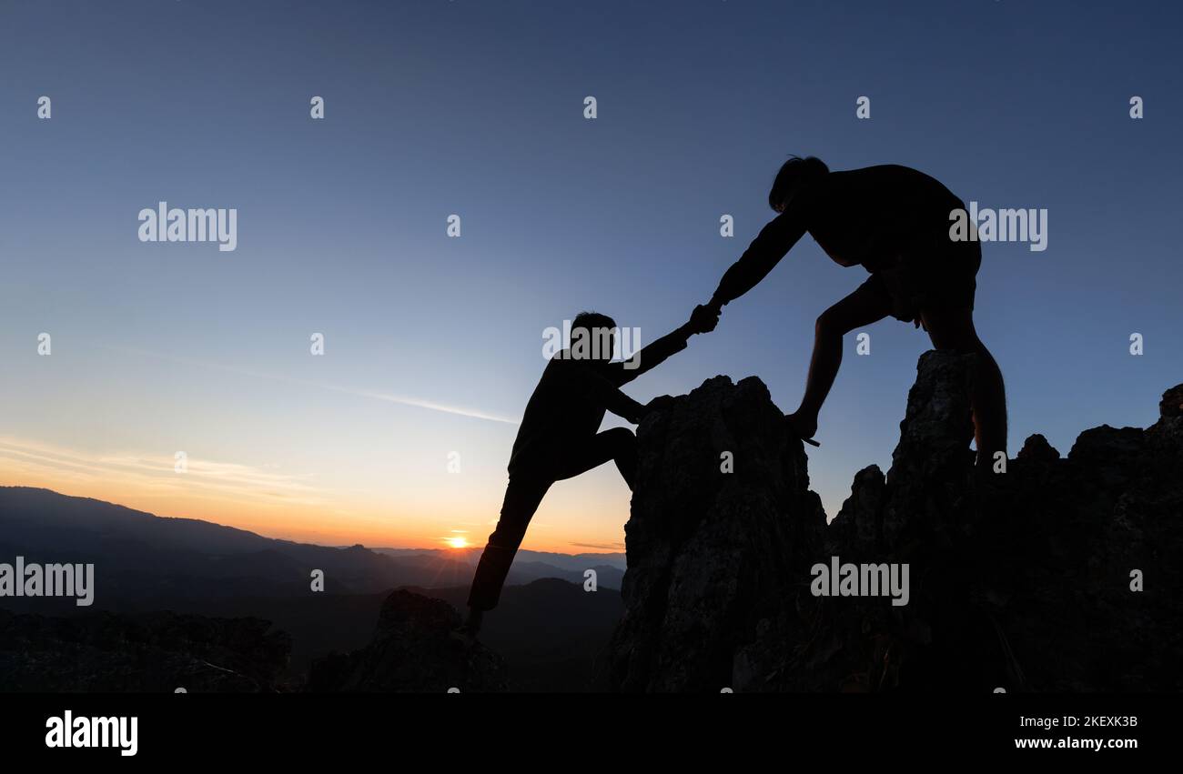 Silhouette der helfenden Hand zwischen zwei Kletterer. Paar Wandern helfen einander Silhouette in Bergen mit Sonnenlicht. Die Männer helfen, die Leute hochzuziehen f Stockfoto