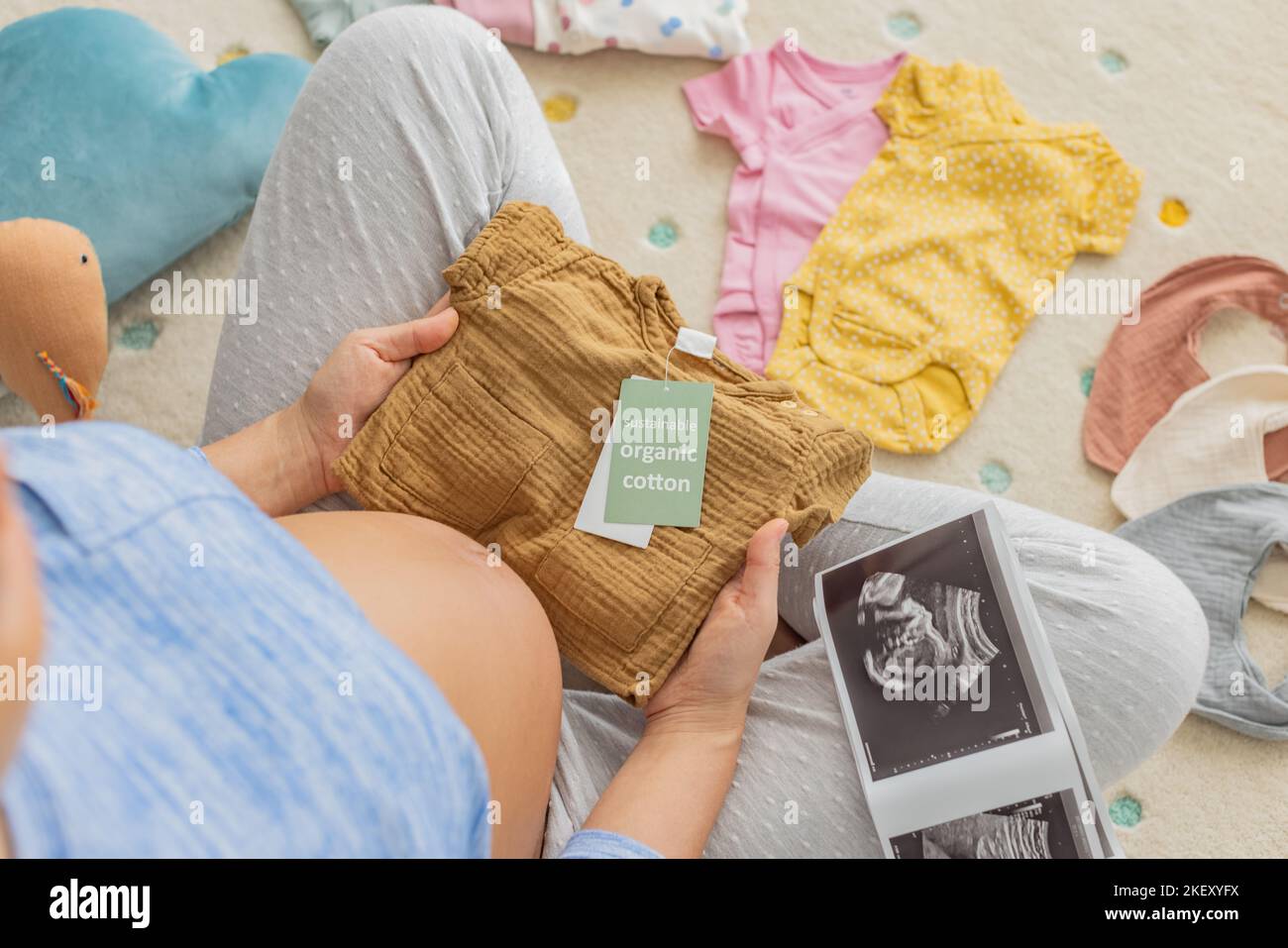 Babykleidung aus Bio-Baumwolle. Schwangerin kauft nachhaltige, gesunde Babykleidung während der Schwangerschaft ein. Frau zeigt schwanger Bauch Baby bump Stockfoto
