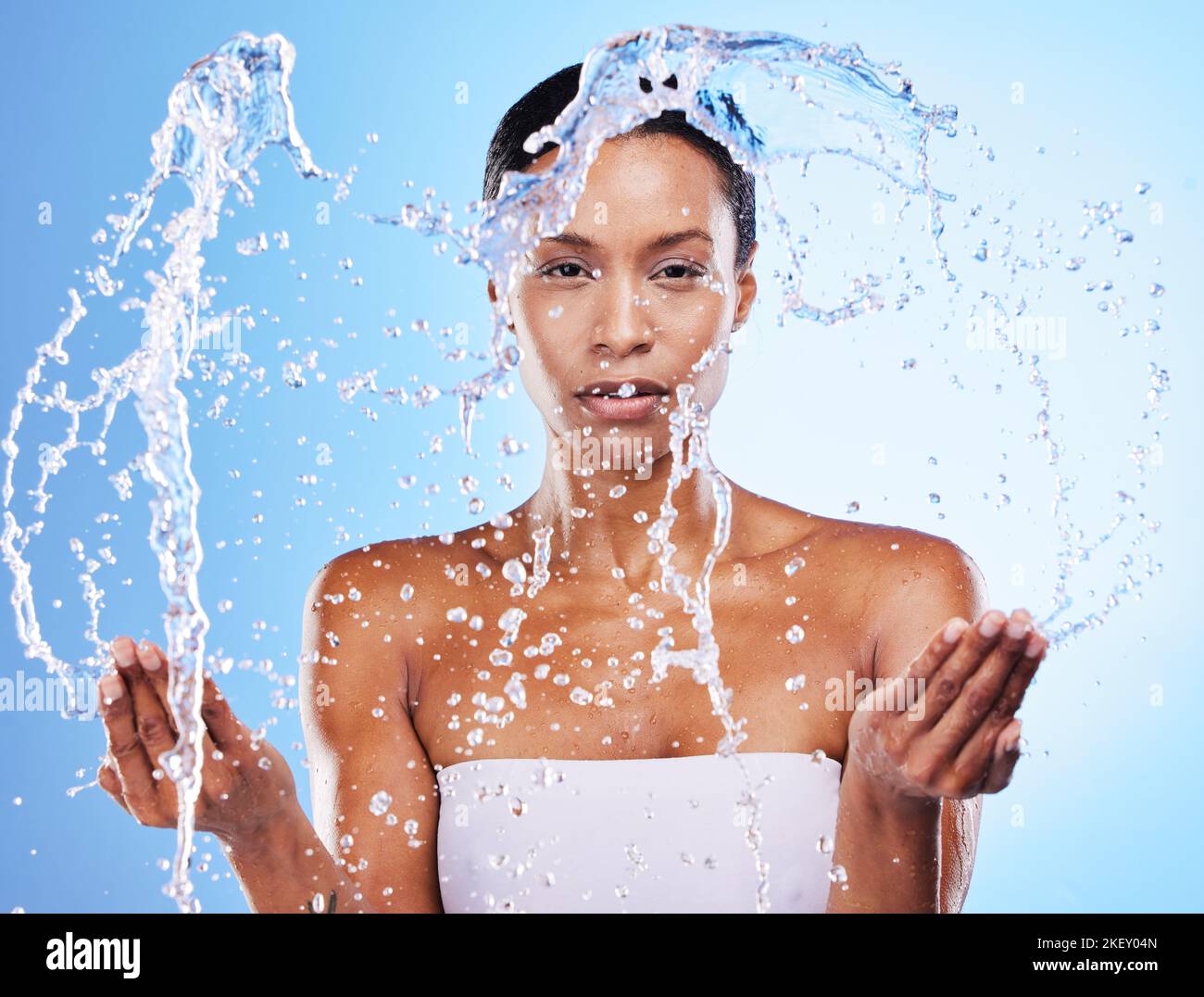 Sauber, Schönheit und Wasser spritzen mit schwarzer Frau in der Dusche und Pflege Porträt vor blauem Studio-Hintergrund. Hygiene, frisch und Wasser mit Spritzer Stockfoto