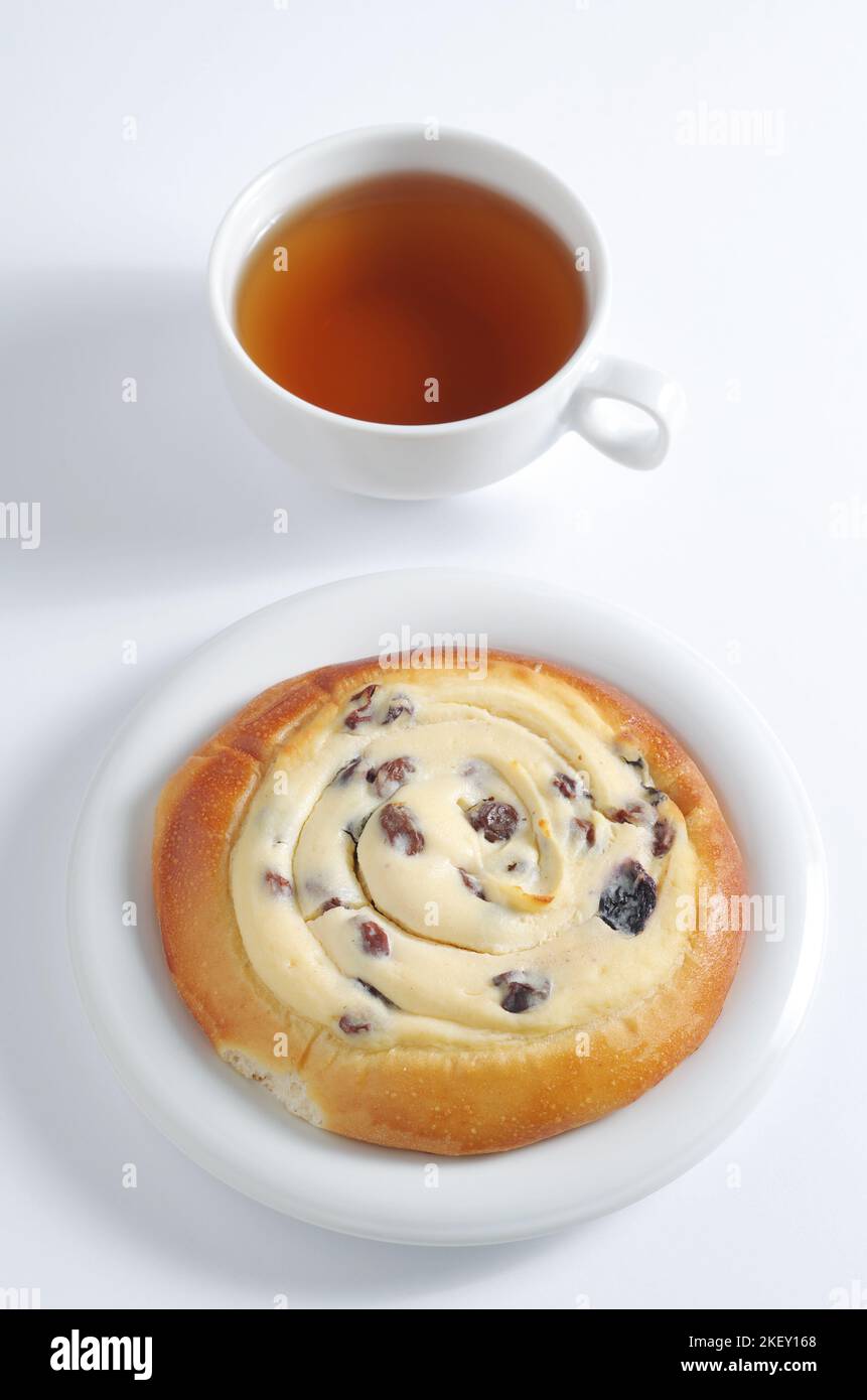 Leckeres Brötchen mit Quark und einer Tasse Tee auf weißem Hintergrund Stockfoto