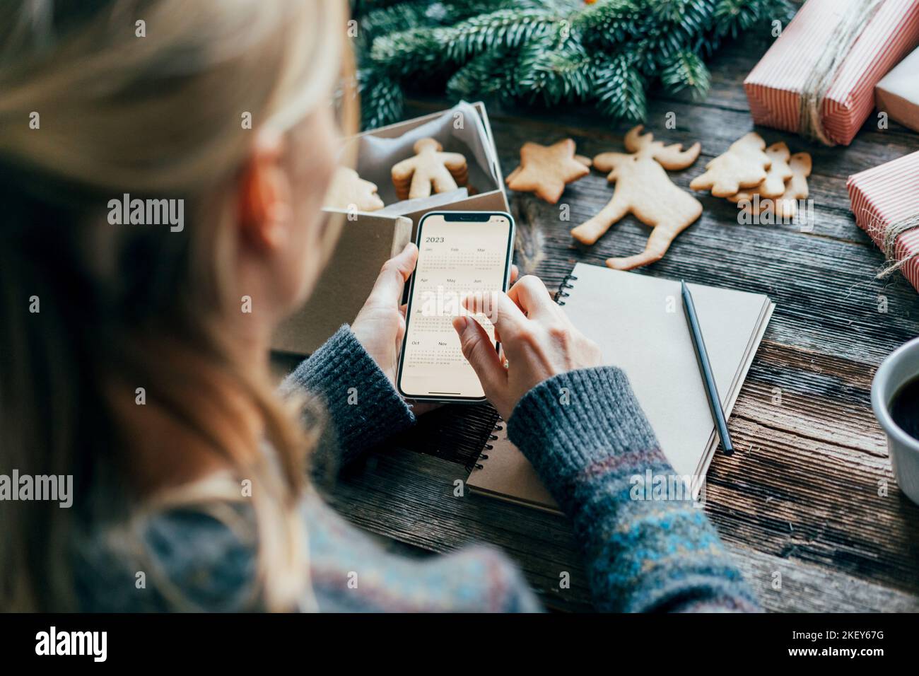 Eine Frau macht Pläne für das neue Jahr 2023 und hält ein Telefon mit einem Kalender auf dem Bildschirm. Stockfoto