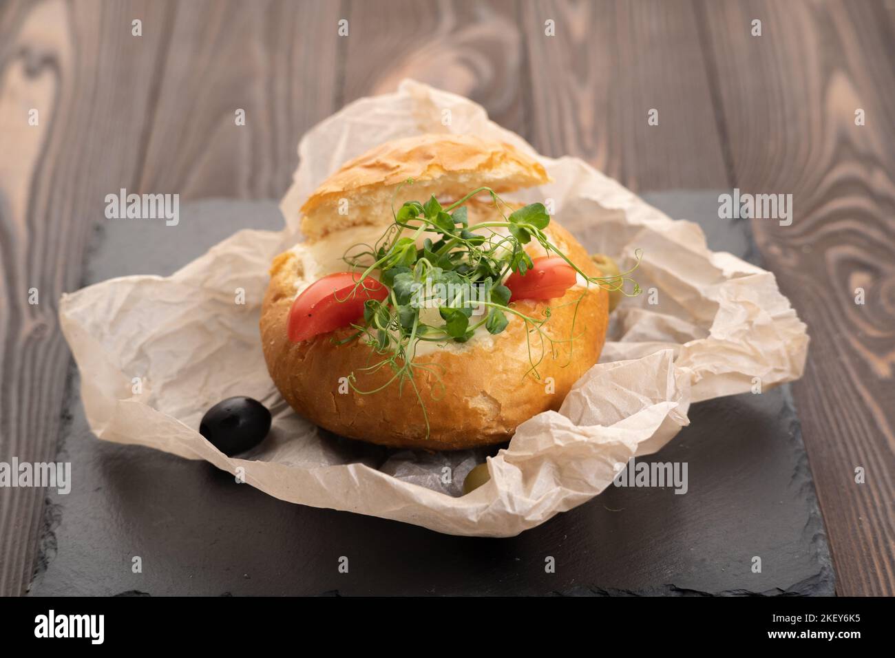 Brotschale gefüllt mit Pilzen, Garnelen, Käse und Bolognese-Sauce zum Mittagessen. Julienne in einem Brötchen Stockfoto