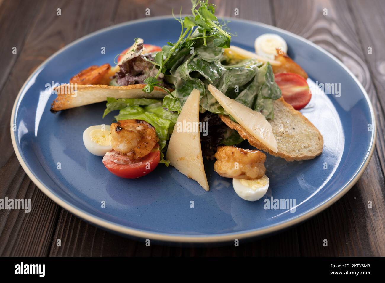 Frischer Caesar-Salat auf blauer Schüssel mit Parmesankäse und Garnelen. Stockfoto