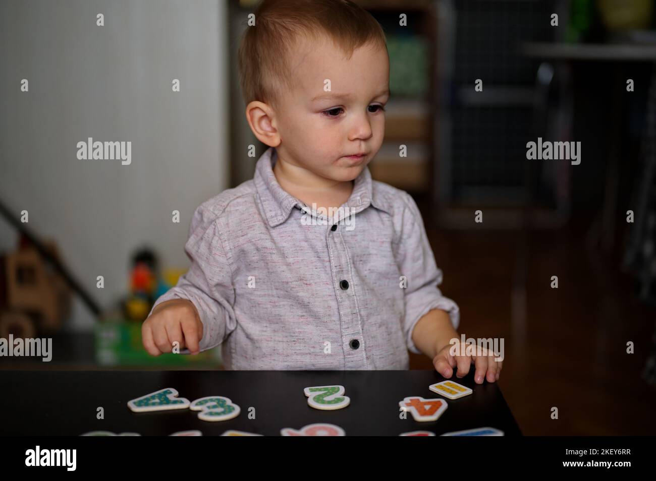 Porträt eines niedlichen kleinen Jungen, der mit Buchstaben und Zahlen auf einem Tisch spielt Stockfoto