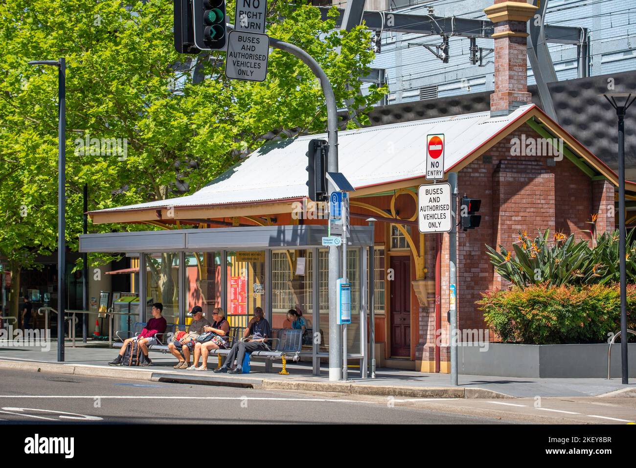 An einer Bushaltestelle in Chatswood, Sydney, Australien, sitzen und warten Menschen, teilweise beschattet von der starken australischen Sonne Stockfoto