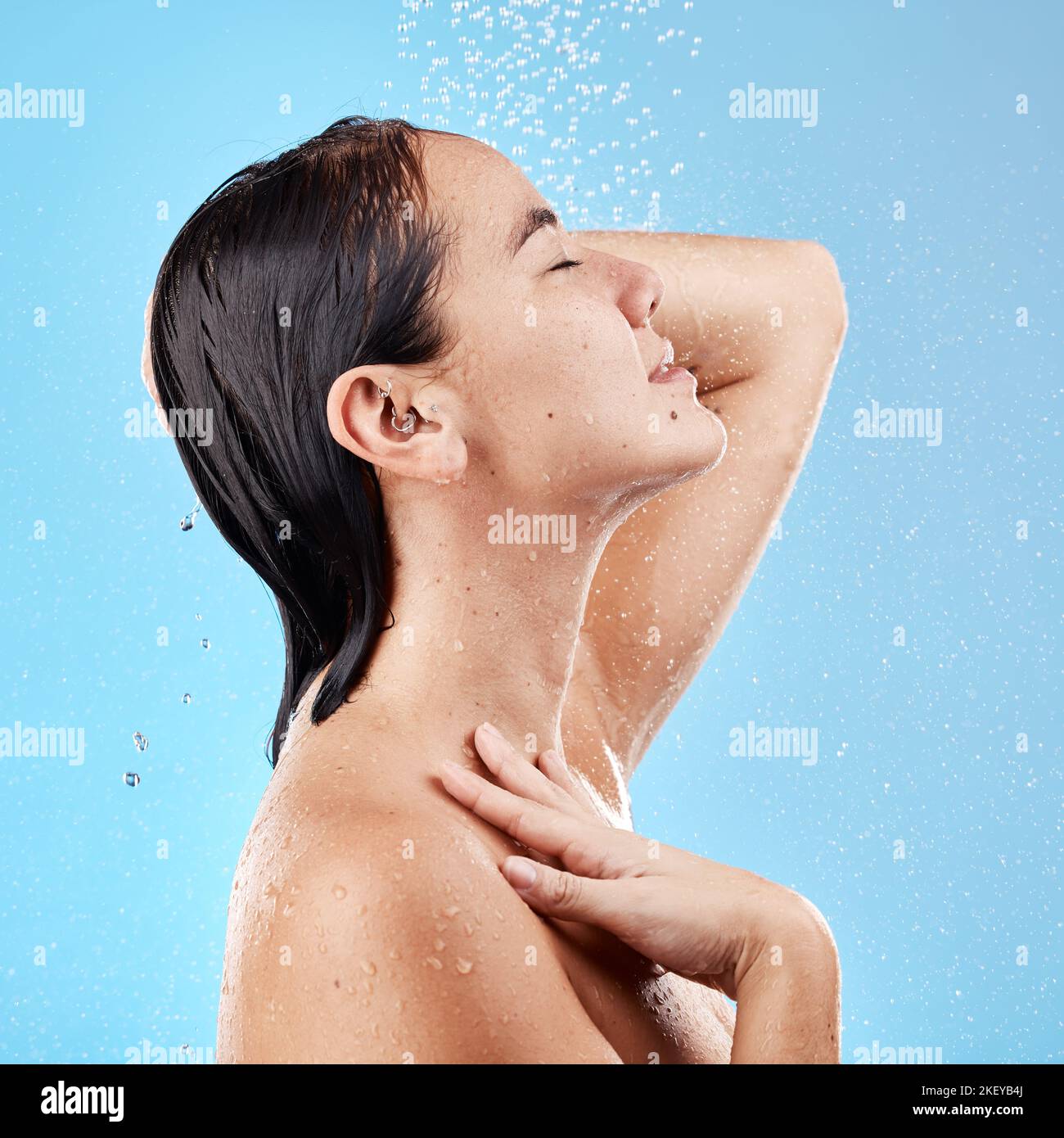 Frau, Dusche und Hautpflege Hydratation für die Hygiene, waschen oder reinigen vor einem blauen Studio Hintergrund. Weibliche entspannen in Zufriedenheit für Wasser, Schönheit und Stockfoto