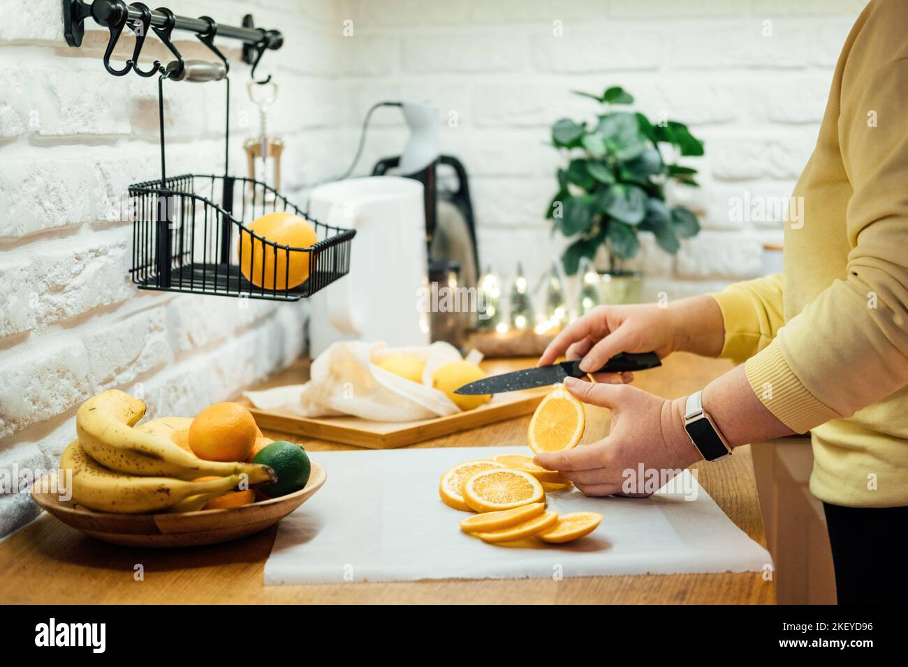 So trocknen Sie Orangenscheiben für das Holiday Decor. Verfahren zum Trocknen von Orangenscheiben im Ofen. Frau schneidet Scheiben von Orangen- und Zitrusfrüchten zum Trocknen Stockfoto