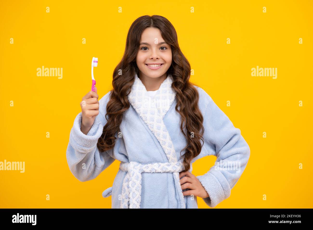 Morgens Zähne putzen. Teenager-Mädchen putzt ihre Zähne über isolierten gelben Hintergrund. Tägliche Hygiene Teenager Kind halten Zahnbürste, morgendliche Routine Stockfoto