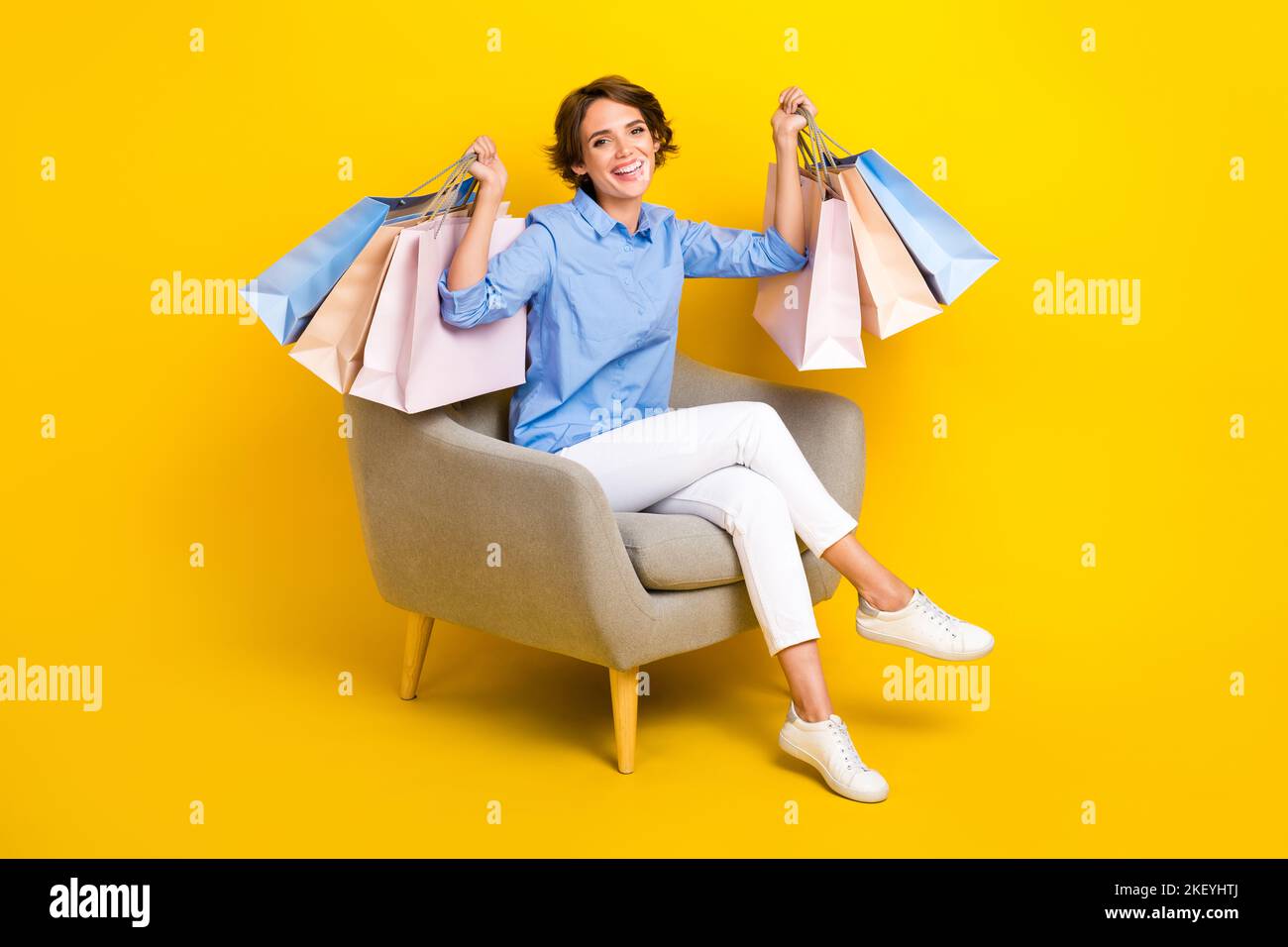 In voller Länge Foto von lustigen fröhlichen Dame tragen blaues Hemd steigende Käufer isoliert gelbe Farbe Hintergrund Stockfoto