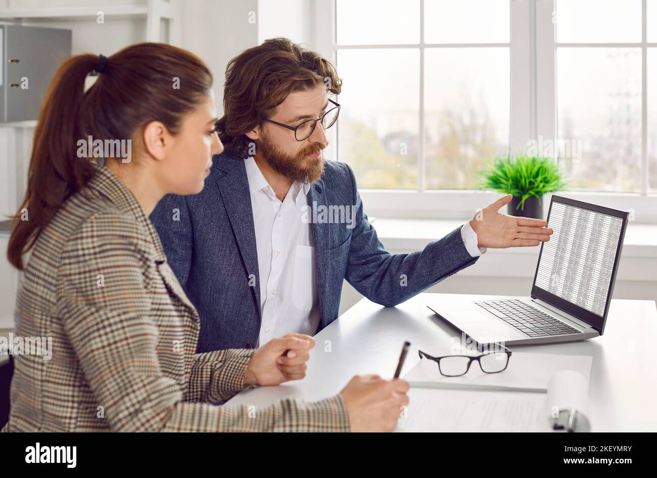 Unternehmensberater, der mit seinem Kunden spricht und Tabellenkalkulationen auf einem Laptop vorführt Stockfoto