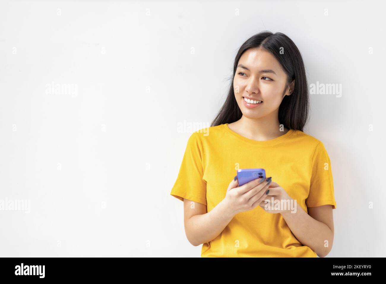 Junge glückliche asiatische Frau hält Handy wegschauen und lächeln auf weißem Hintergrund. Speicherplatz kopieren Stockfoto