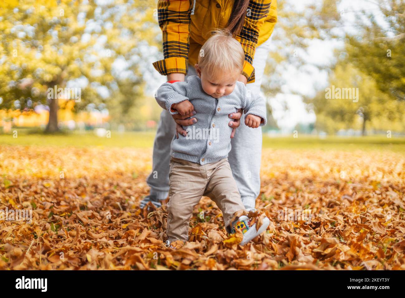 Junge Mutter lehrt ihr kleines Kind zu gehen kleines Baby erste Schritte, Familienzeitkonzept Stockfoto