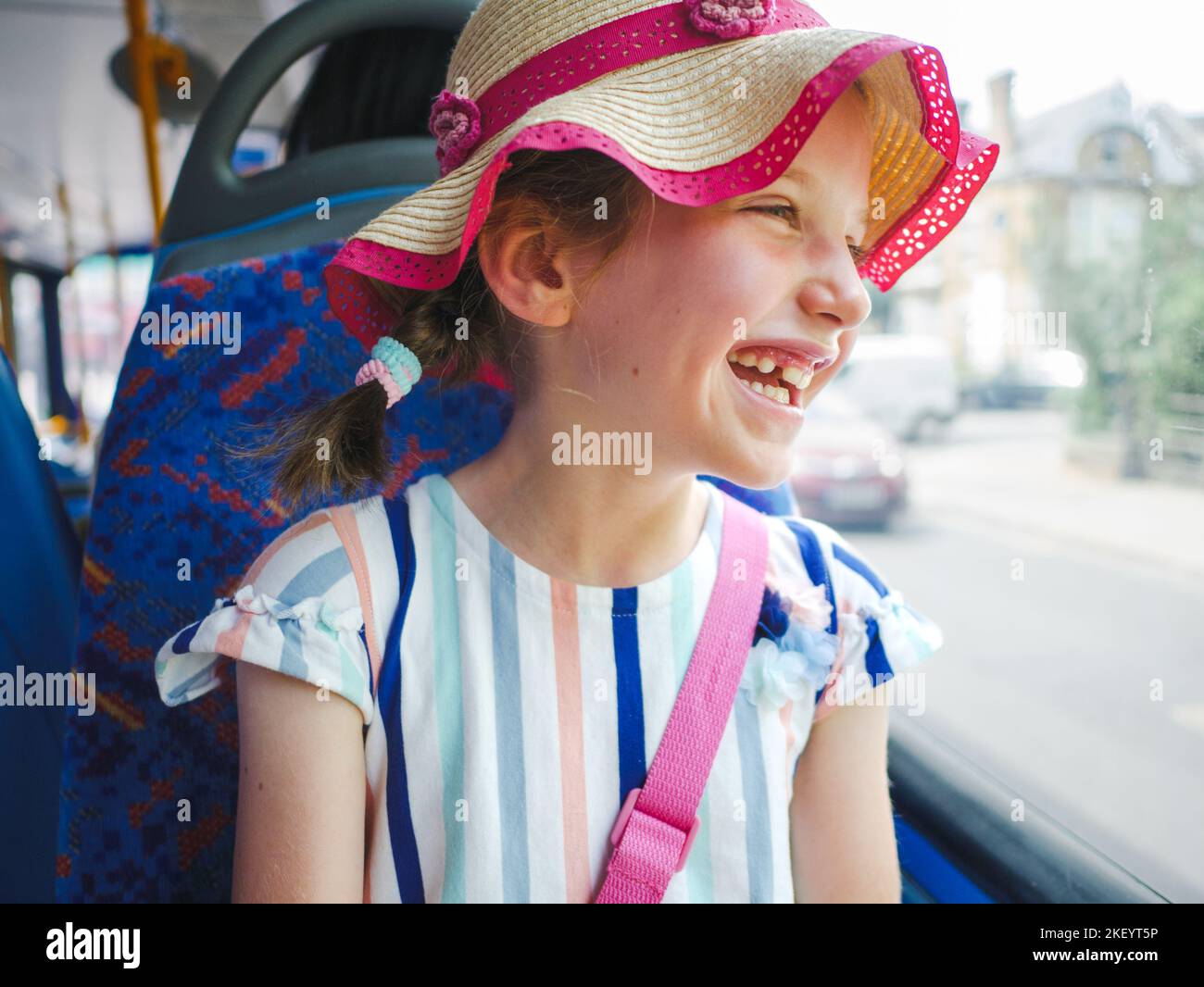 Lächelndes, fröhliches junges Mädchen, das aus dem Fenster in einen Bus schaut, London, Großbritannien Stockfoto
