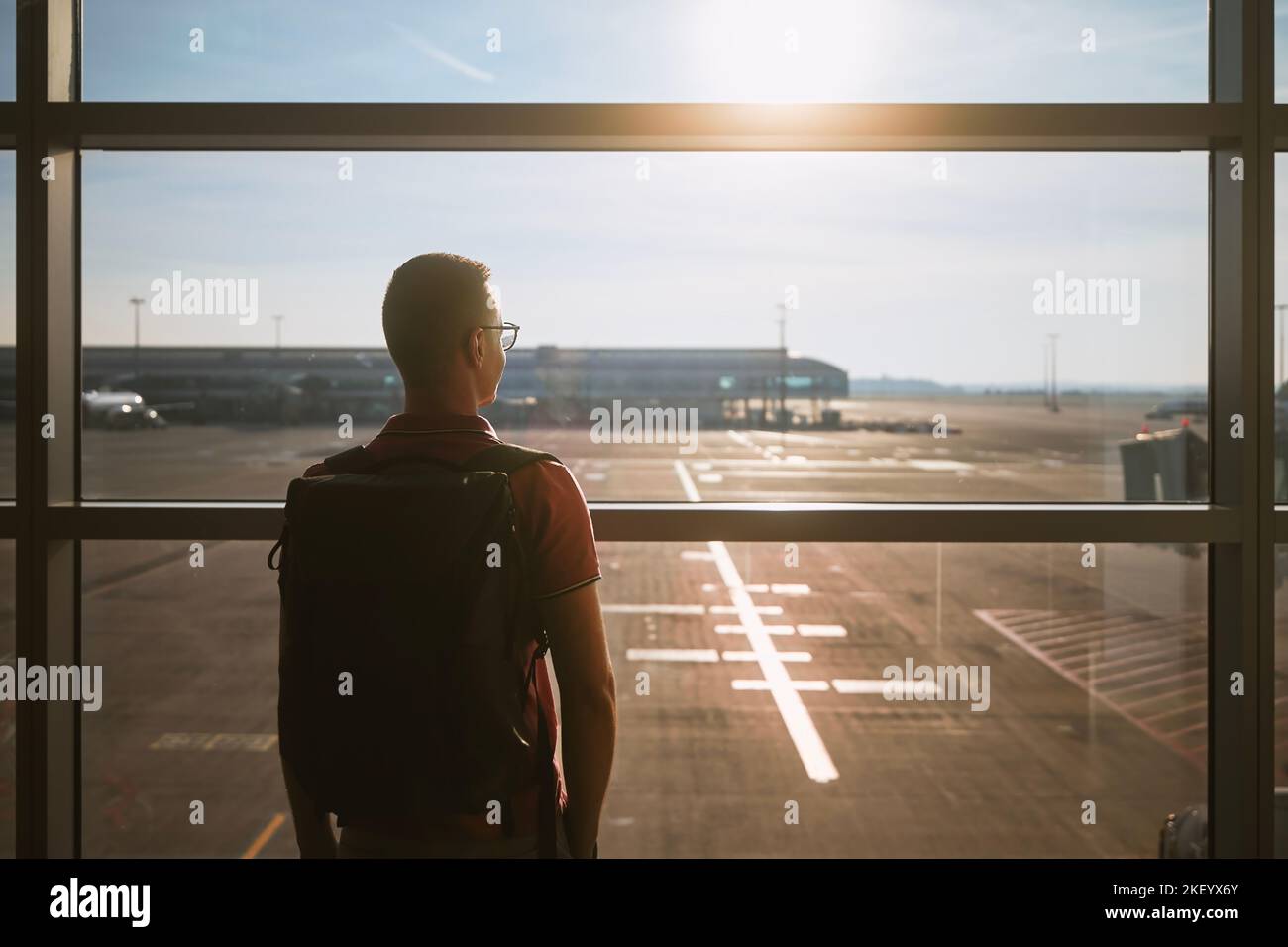 Mann reist mit dem Flugzeug. Rückansicht des Passagiers während des Wartens am Flughafenterminal. Stockfoto