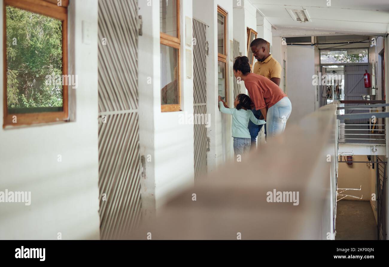 Tierheim, Familie und Eltern verbinden sich mit ihrem Kind, während sie gemeinsam Gemeinschaftsdienste leisten. Mutter, Vater und Kind schauen durch ein Fenster Stockfoto