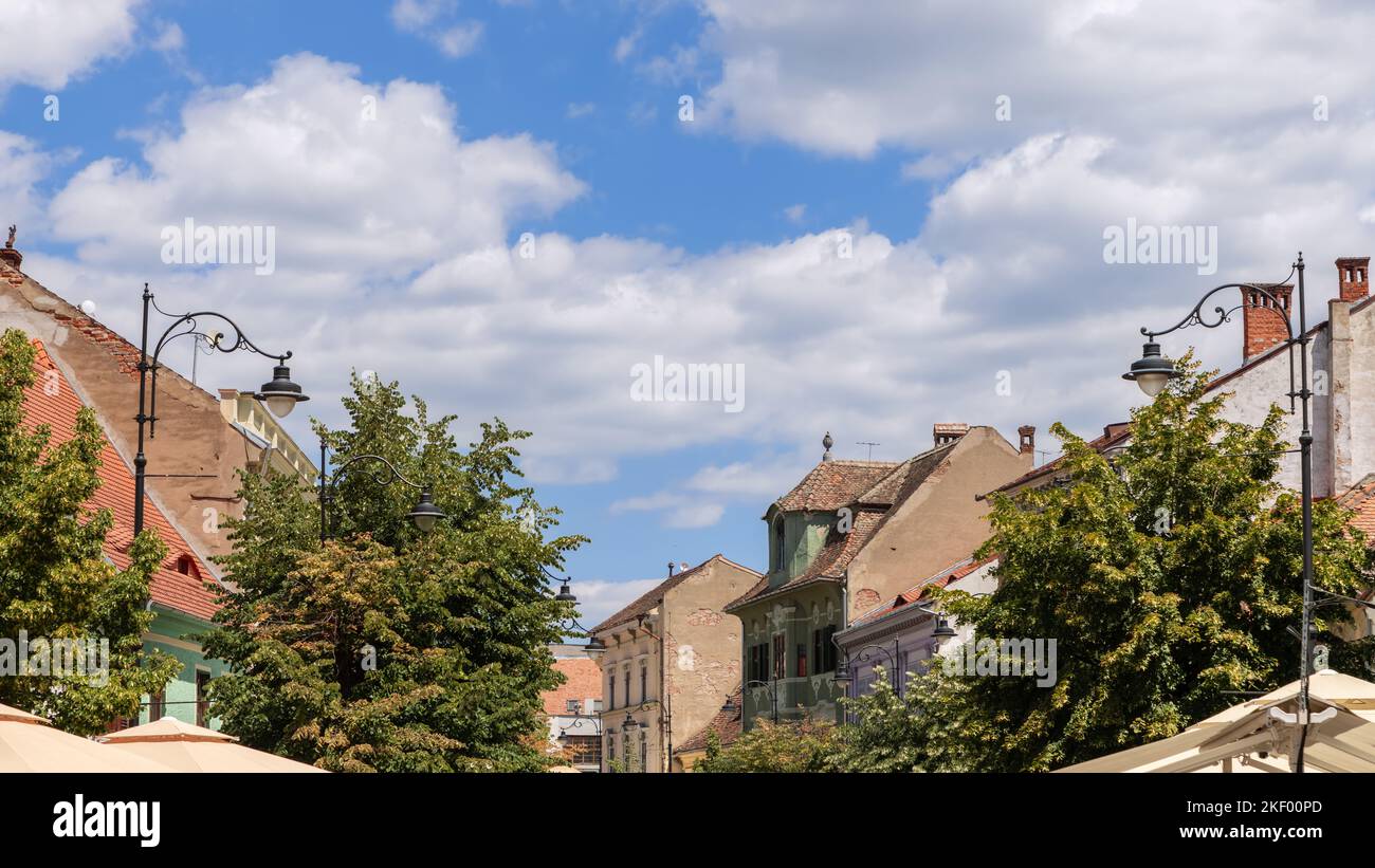 Alte Gebäude der mittelalterlichen Stadt voller verschiedener Architekturstile, Laub, Elektrokabel, blauer Himmel und weltberühmte Augen von Sibiu (Ochii Sibi Stockfoto