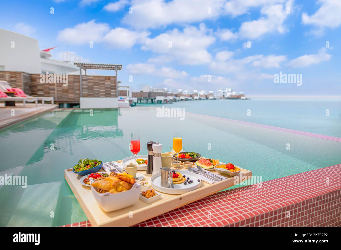 Frühstück im schwimmenden Swimmingpool. Luxuriöser Sommerurlaub oder Flitterwochen. Resort Hotel Gourmet leckeres Essen nahe am Meer mit Horizont Stockfoto