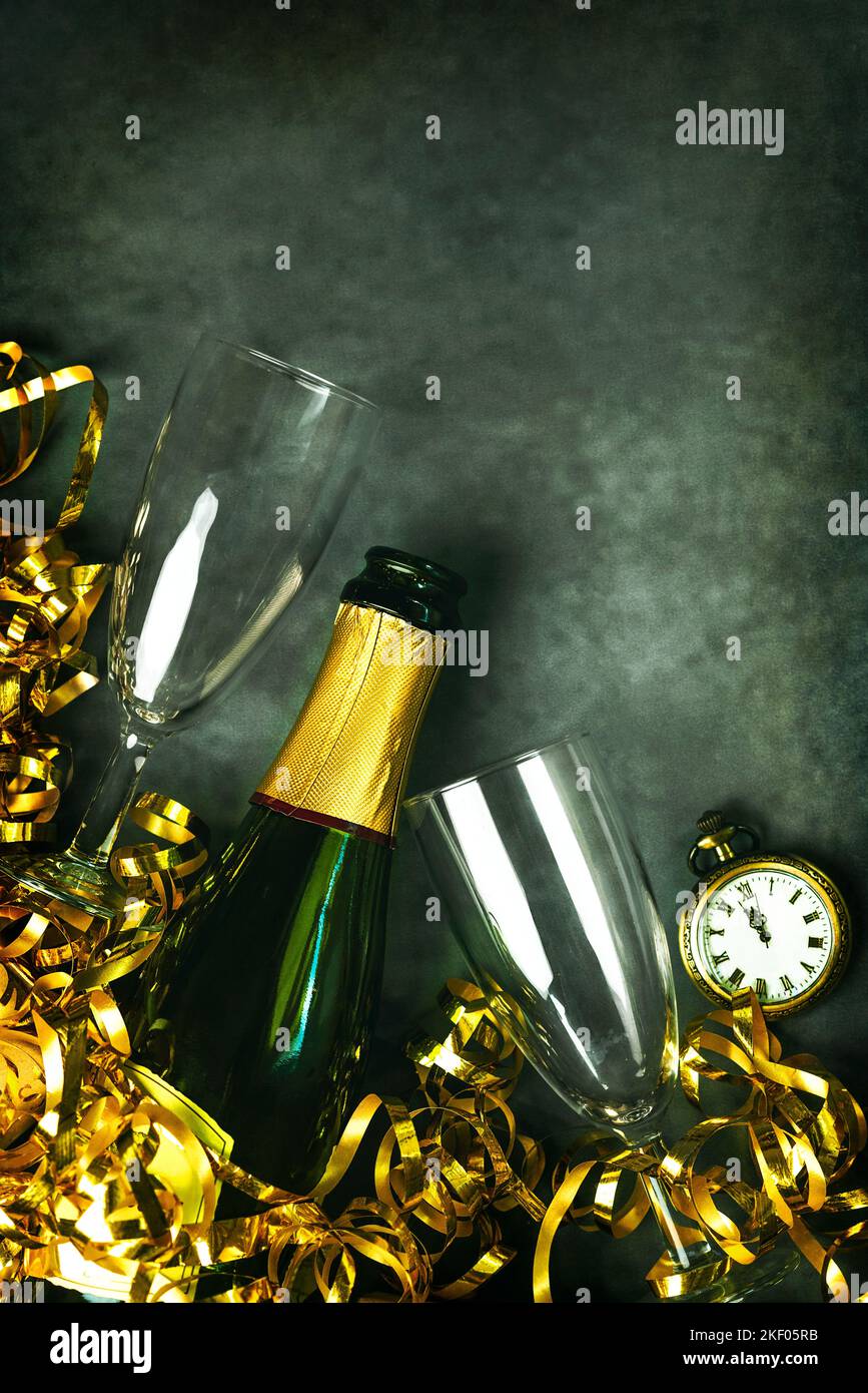 Frohes neues Jahr. Champagnerflasche mit zwei Gläsern, goldenen Luftschlangen und antiker Uhr mit Kopierfläche über Grunge-Hintergrund. Silvesterfeier Stockfoto