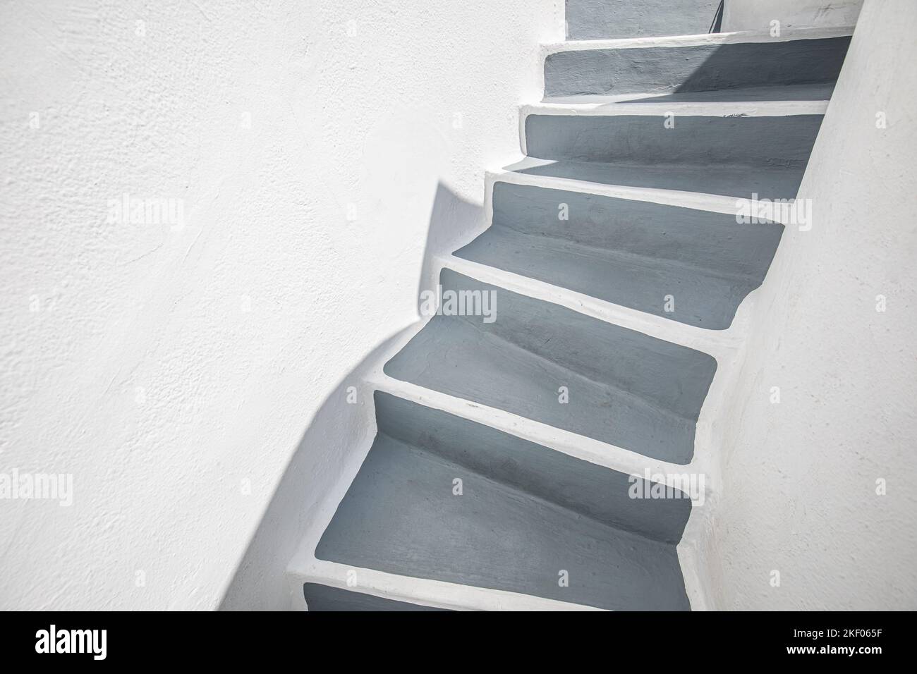 Leere Steintreppe in der Nähe der weißen Mauer, abstrakte Nahaufnahme auf Santorini Island, Griechenland. Weiße Architektur mit grauen Stufen. Minimale Gebäudeteile Stockfoto