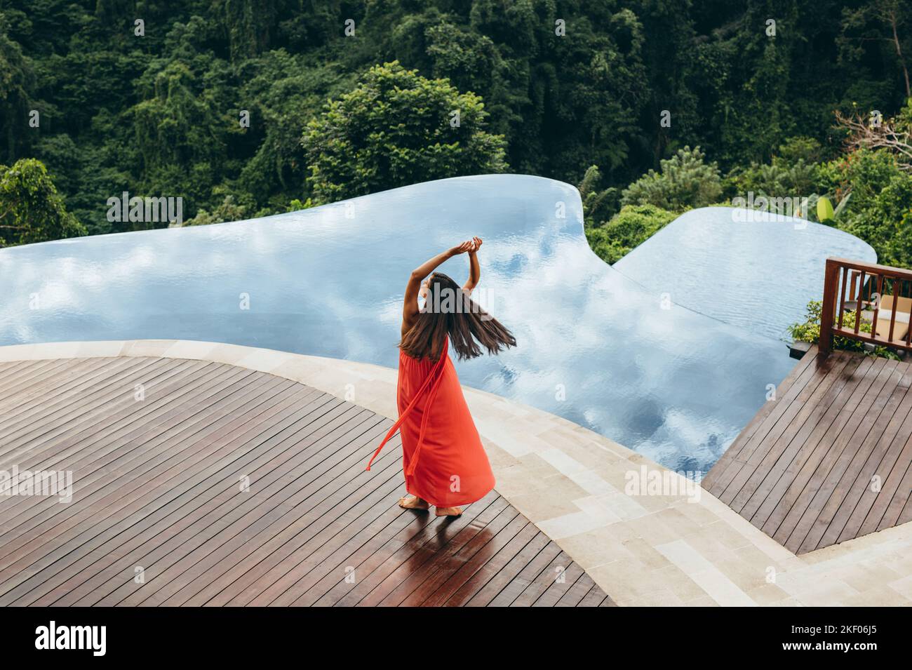 Luftaufnahme einer jungen Frau, die ihren Urlaub im Luxusresort genießt. Weibliche Model tanzt am Pool. Stockfoto