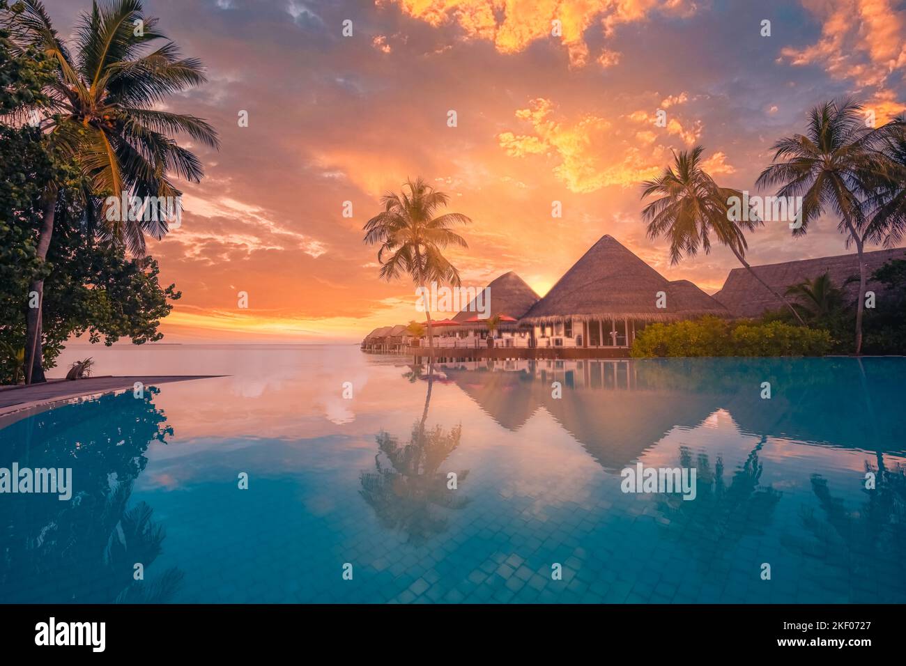 Touristische Landschaft bei Sonnenuntergang. Luxuriöses Strandresort mit Swimmingpool, Reflexionsstrand mit Palmen und Sonnenstrahlen. Ein fantastischer Reisehintergrund Stockfoto