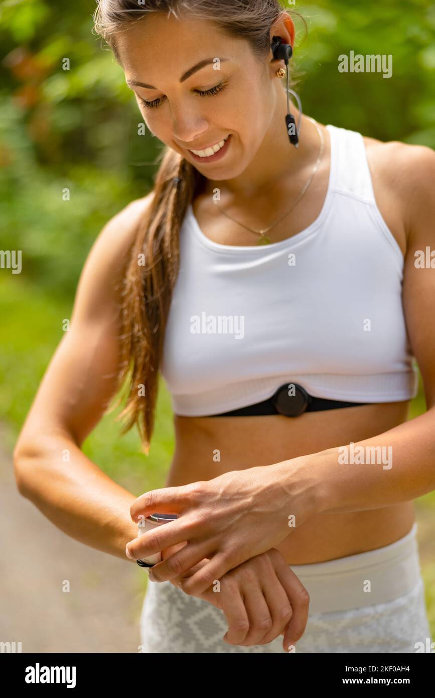 Porträt einer Frau, die während des Trainings ein Fitness-Smart-Watch-Gerät verwendet Stockfoto