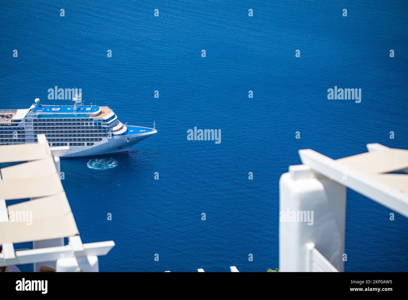 Kreuzfahrtschiff auf tiefblauem Meer auf der Insel Santorin, griechische Bucht mit kleinen Transportbooten. Sommerferien, Touristentourismus Menschen im Mittelmeer Stockfoto