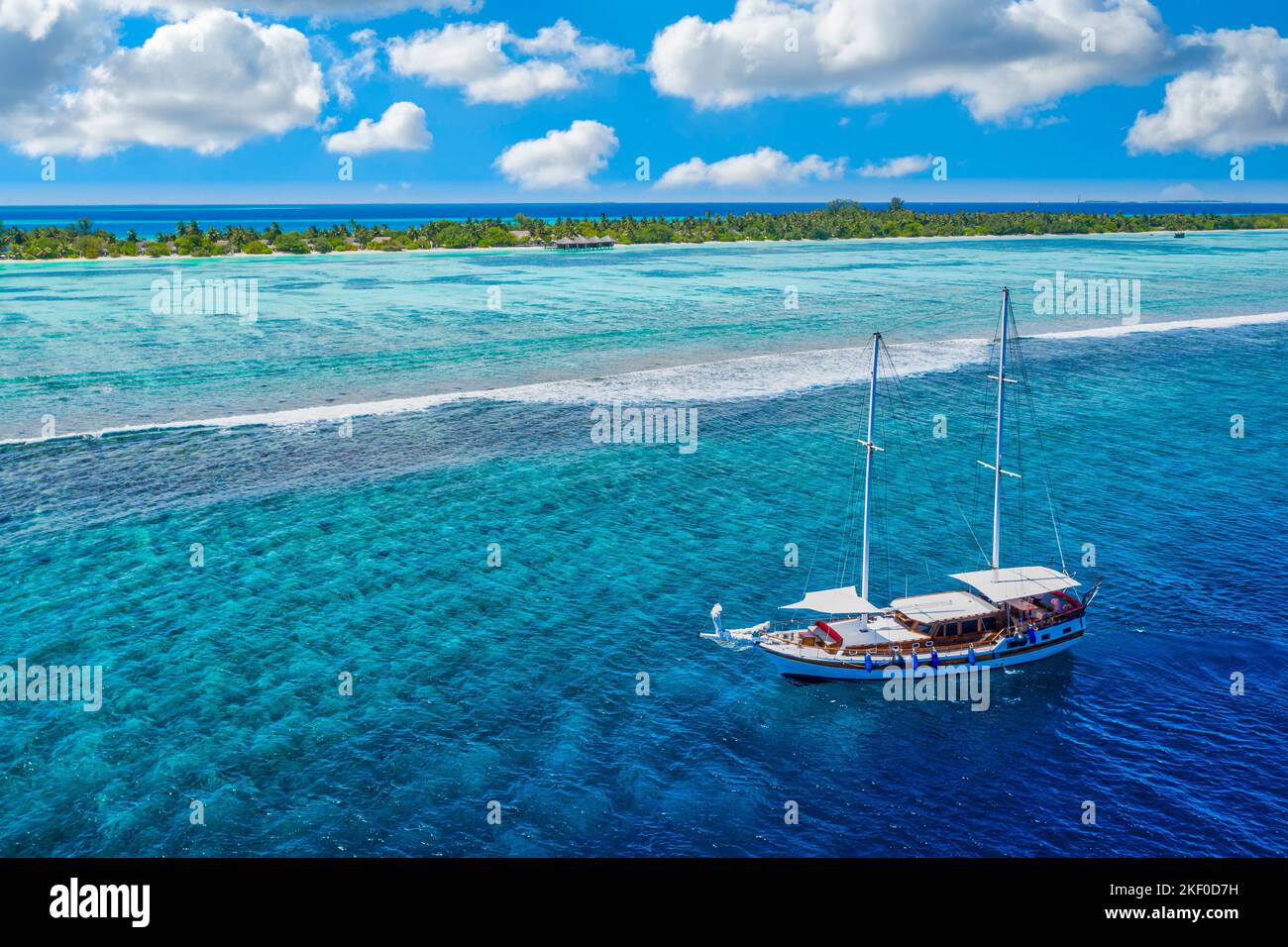 Kleine Yacht, die über das tropische Meer über das Korallenriff in der Lagune des Indischen Ozeans segelt. Exotische Insellandschaft aus der Vogelperspektive, atemberaubendes Naturabenteuer Stockfoto