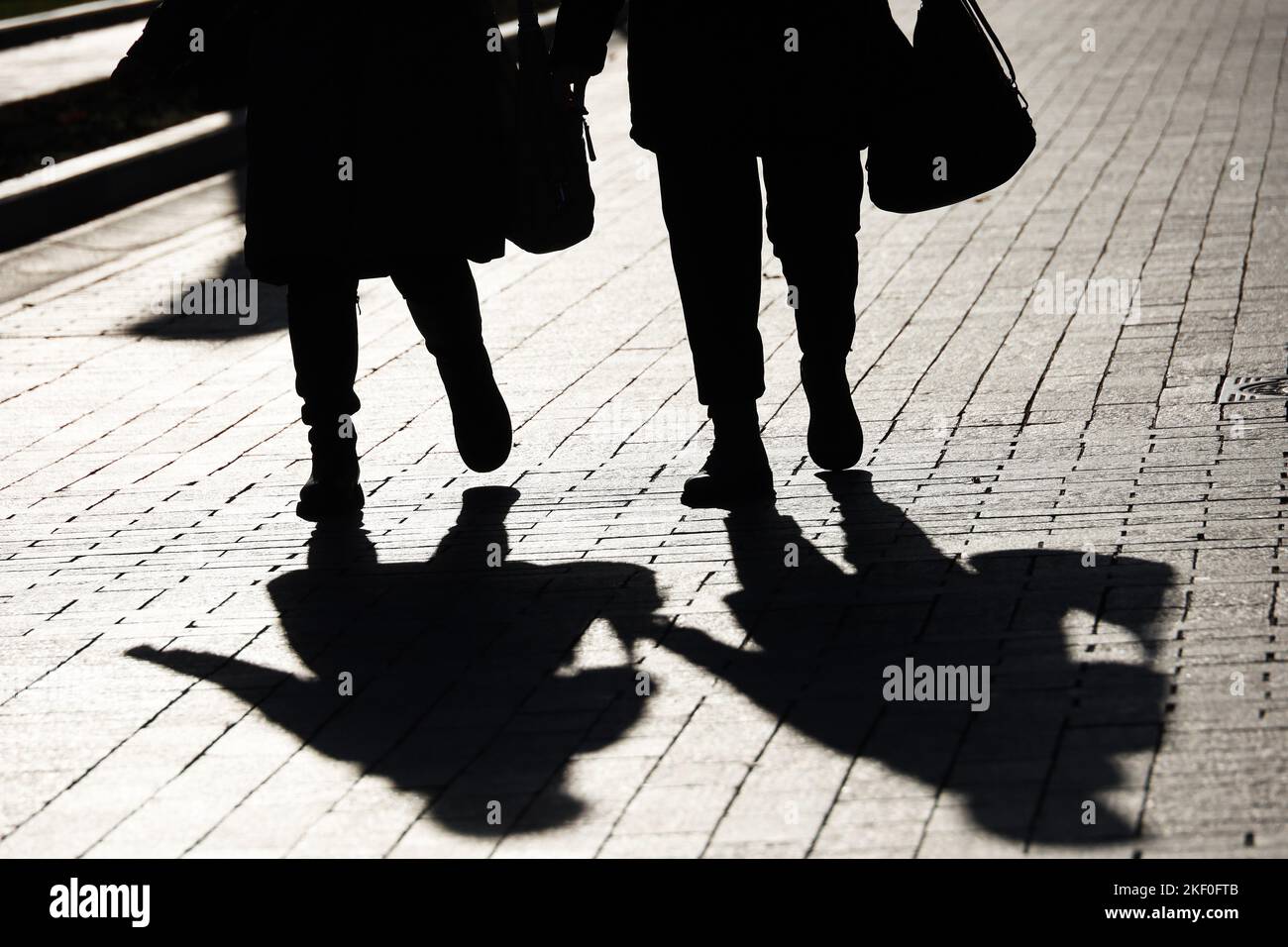 Silhouetten und Schatten von zwei Frauen, die auf der Stadtstraße spazieren. Konzept der weiblichen Freundschaft, Gesellschaft und Bevölkerung Stockfoto