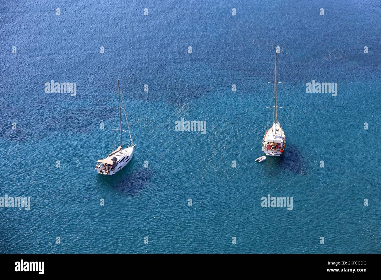 Luftaufnahme zu Yachten mit abgesenkten Segeln auf blauer Meeresoberfläche. Zwei Segelboote liegen vor Anker, Hintergrund für Reisen und Urlaub Stockfoto