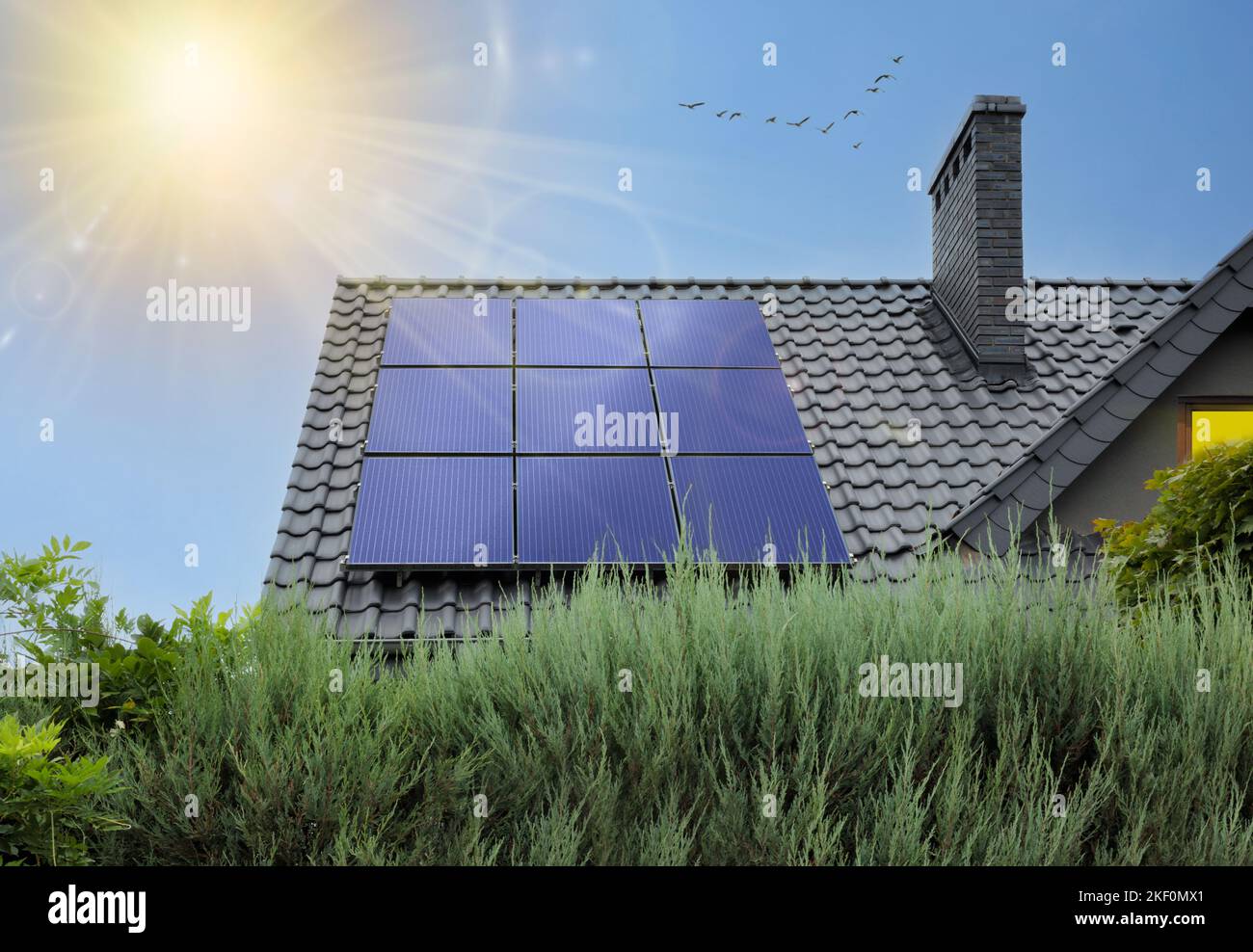 Schönes modernes Haus mit Sonnenkollektoren. Klarer Himmel, Sonne. Haus mit Photovoltaik auf dem Dach und Sonnenstrahlen. Stockfoto