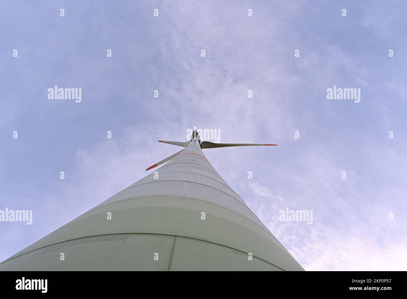 Niedrige Sicht auf Propeller und Säule einer Onshore-Windturbine gegen blauen Himmel, die den Bedarf der Einwohner mit erneuerbarer Energie versorgt. Stockfoto