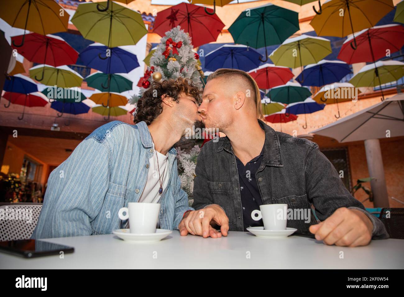 Das homosexuelle Paar trinkt während der Weihnachtsfeiertage in einem Café Kaffee. Stockfoto