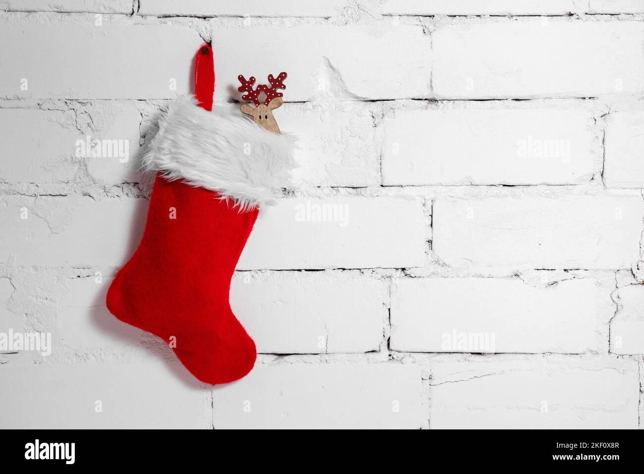 weihnachtssocke mit Hirsch Dekoration hängen auf weißem Backstein Wand Hintergrund. Kopieren Raum Stockfoto