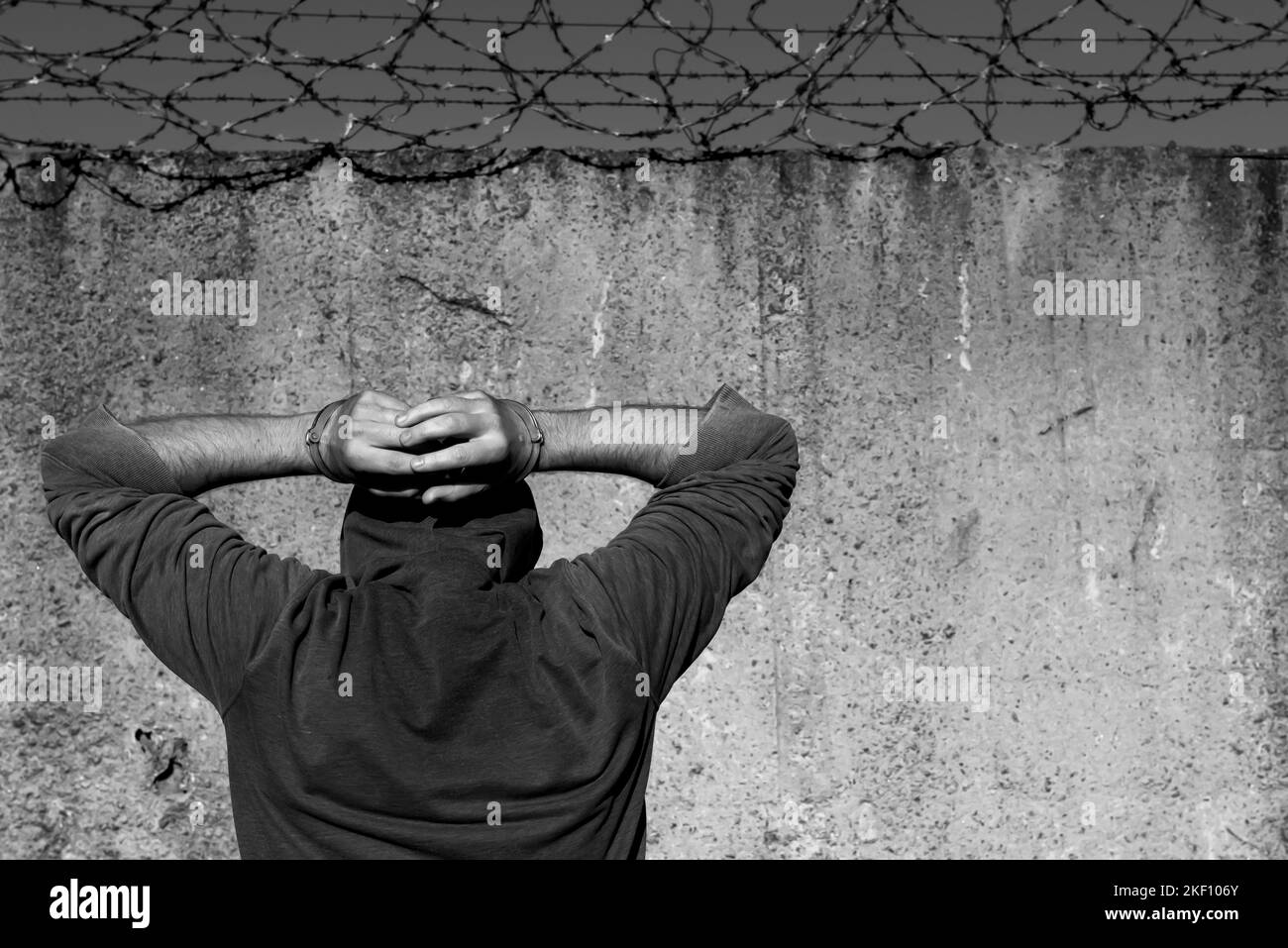 Straftätern im Gefängnis. Ein Mann mit Handschellen steht an einer Stacheldrahtschicht. Gefängnisse. Recht und Ordnung. Handschellen Stockfoto