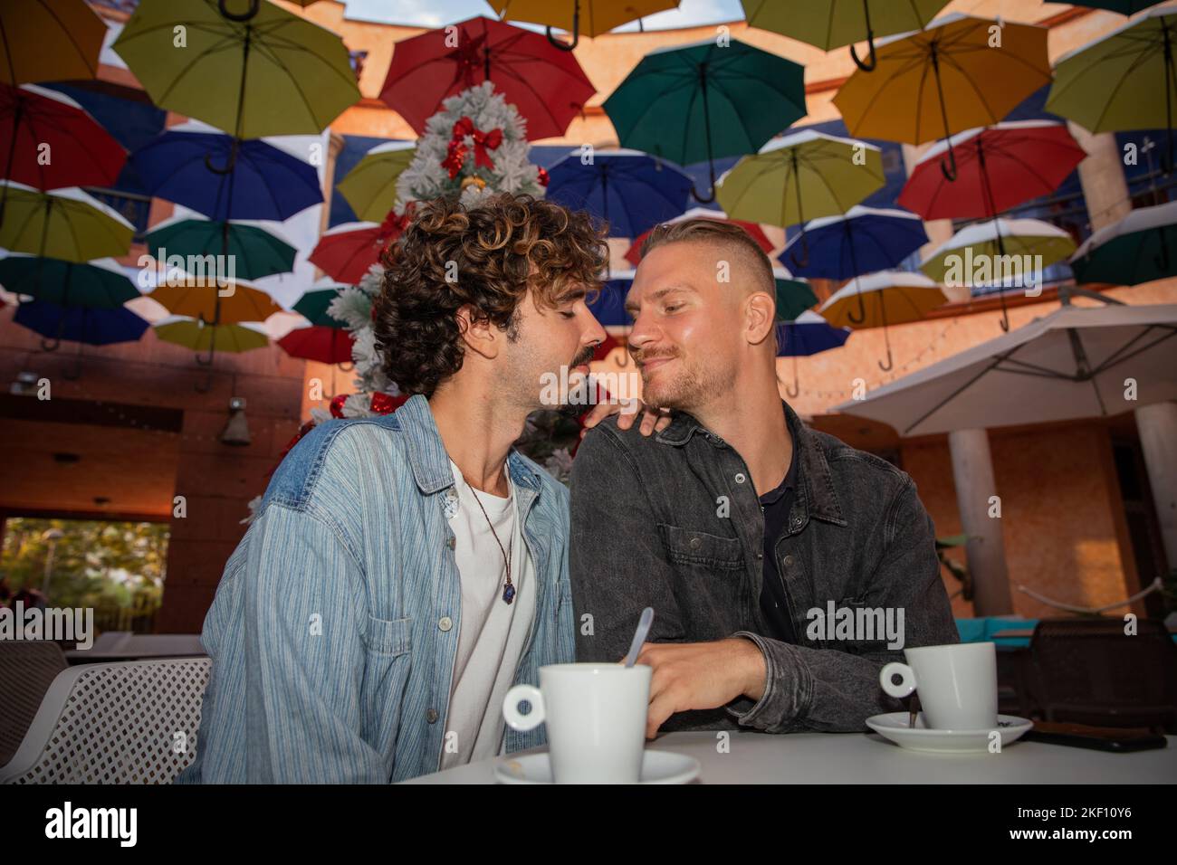 Ein homosexuelles Paar trinkt in der Weihnachtszeit während eines Moments der Zärtlichkeit Kaffee Stockfoto